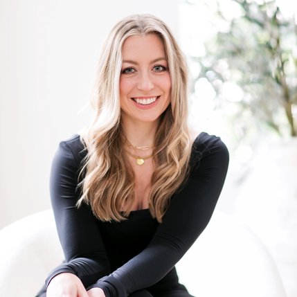 Headshot of Kelli Binnings: a blonde haired, blue eyes woman wearing black in a minimalist setting.