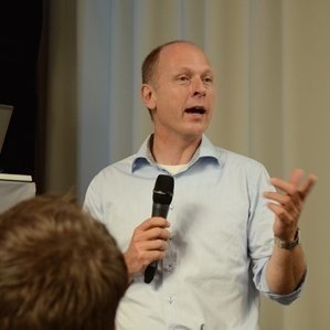 Portrait of Bart Reijs author of Sacrificing Hippocrates at a presentation holding a microphone